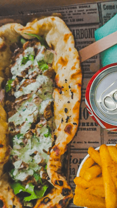 A Punjabi Bytes cheesy naan taco served with seasoned fries and a soft drink